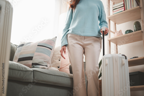 baggage, travel, woman, suitcase, trip, bag, case, holiday, suit, vacation. below angle view portrait of girl dragging a white, pink pastel color suitcase in her room before flight relocation voyage.