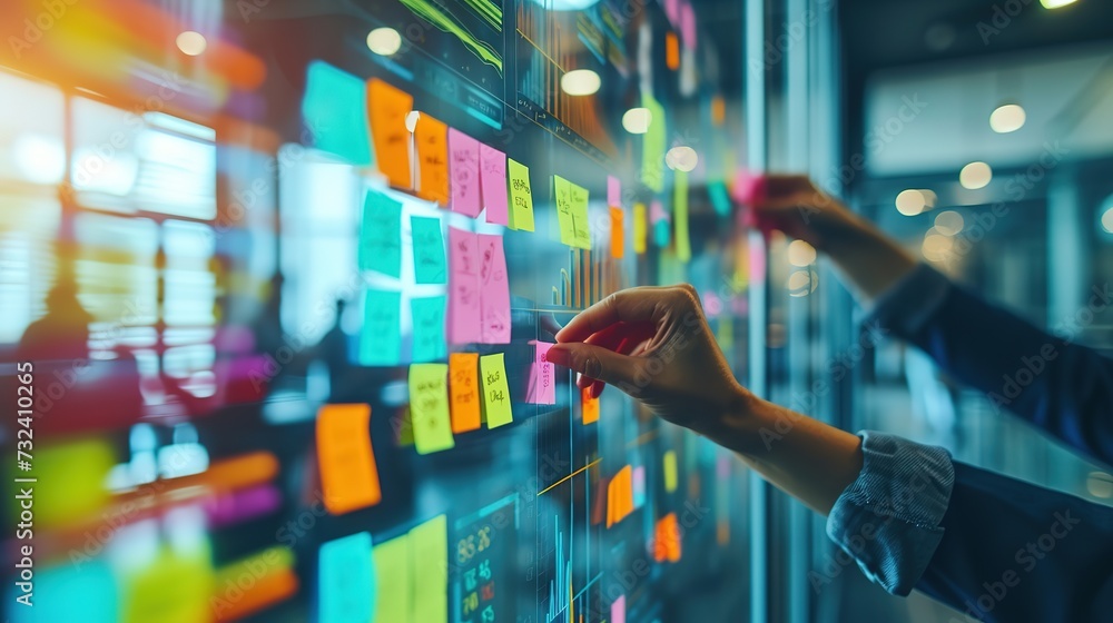 A professional's hands are arranging colorful sticky notes on a glass wall for project management and brainstorming in a modern office. - obrazy, fototapety, plakaty 