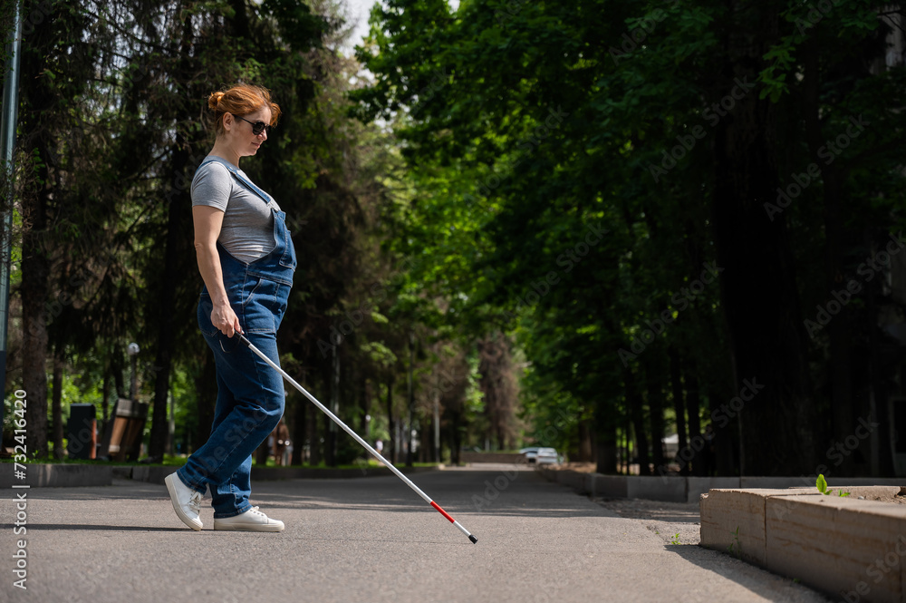 Blind pregnant woman crosses the street with the help of a tactile cane. Blind pregnant woman crosses the street with the help of a tactile cane.