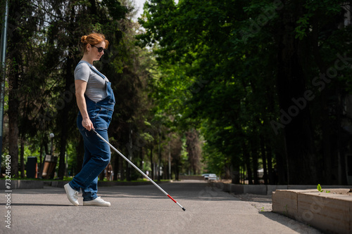 Blind pregnant woman crosses the street with the help of a tactile cane.