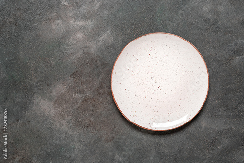 Empty white plate on a dark grunge background. Top view, flat lay, copy space.