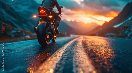 As the biker revs up his vintage motorbike, the sound of the engine fills the air, a testament to the power and freedom of the open road at sunset. photo
