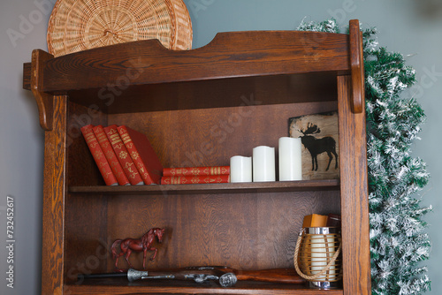 Close-up of a living room cabinet with books and candles on gray background 