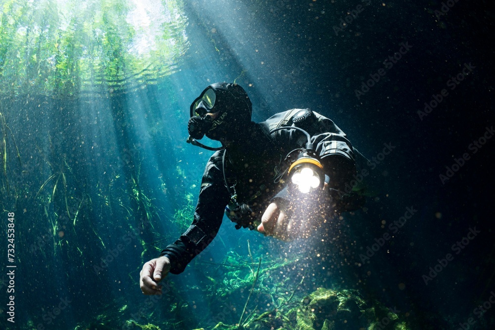 Scuba diver wearing a wetsuit and oxygen tank swimming underwater