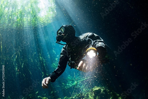 Scuba diver wearing a wetsuit and oxygen tank swimming underwater