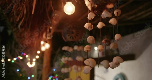 Shell decoration hanging from the ceiling next to the illuminated light bulbs on blurry background photo