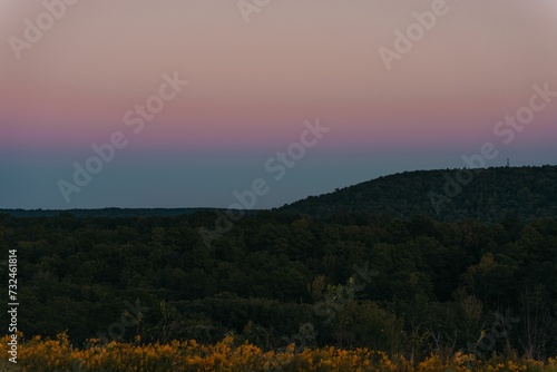 Scenic view of a mountain range covered with green forest at sunset