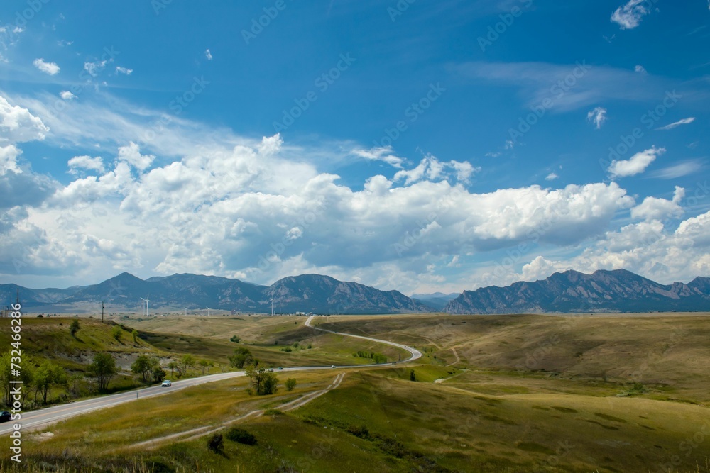 Picturesque country road stretching across the vast prairie, framed by the majestic mountains