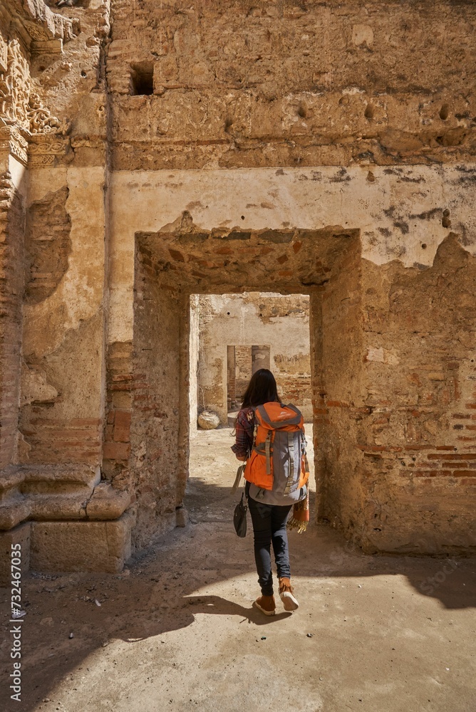 Female traveler with a backpack walking through an open stone archway