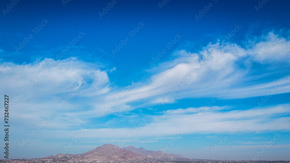 A mountain range against the sky filled with white fluffy clouds