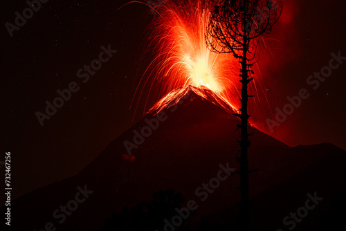 a volcano at night with some red lights on it, and the spewing