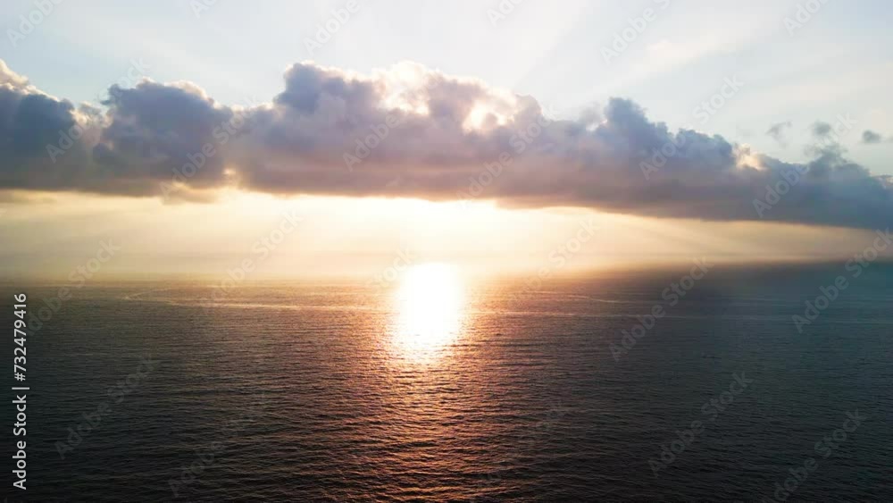 Aerial of the bright golden sunset shining behind the calm sea Aerial of the bright golden sunset shining behind the calm sea