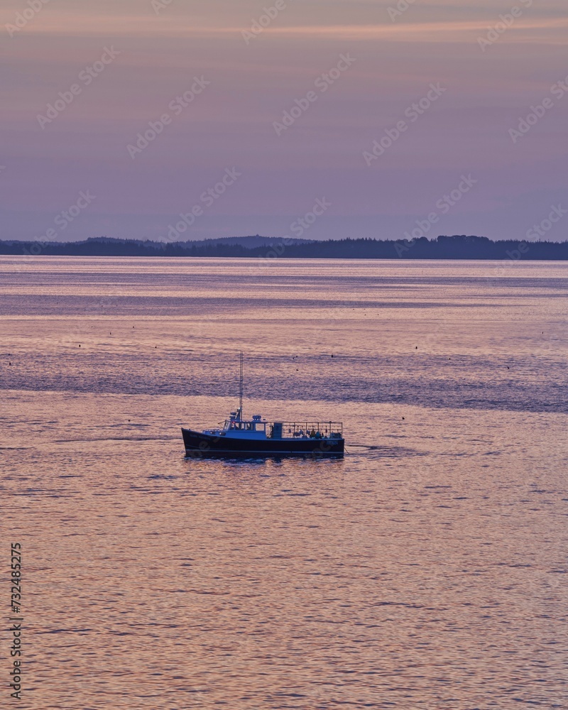 Beautiful sunset view of a small boat sailing on a tranquil sea Beautiful sunset view of a small boat sailing on a tranquil sea