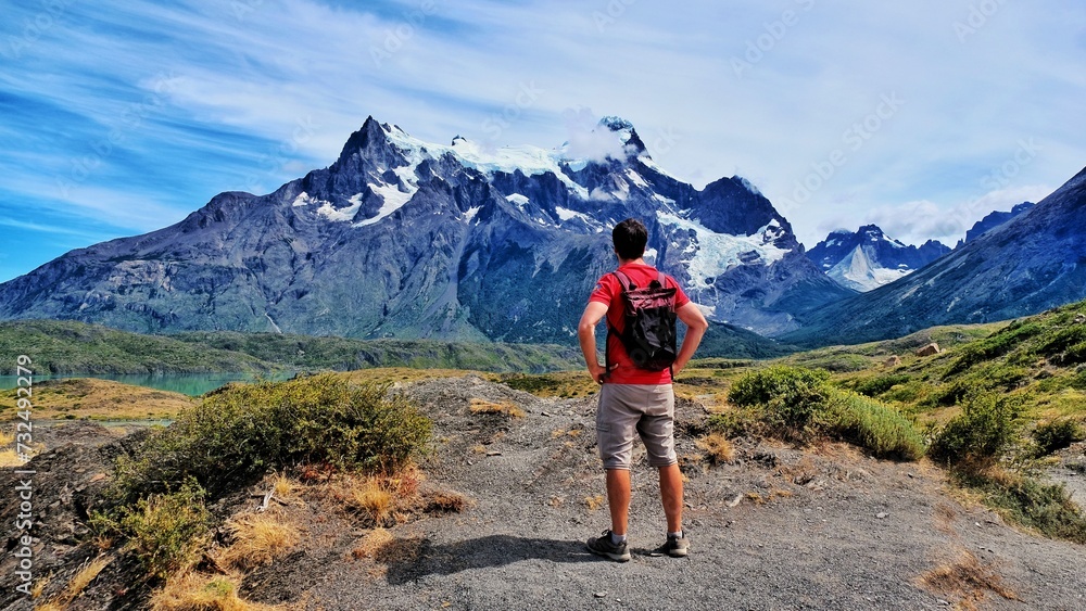 Obraz premium Backpacker stands against the backdrop of majestic mountains. Torres del Paine National Park.