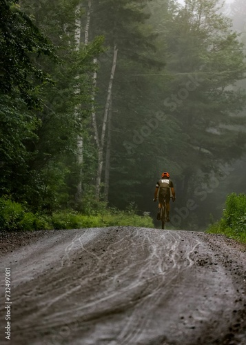 a dirt road surrounded by trees and bushes with a person riding on the bike