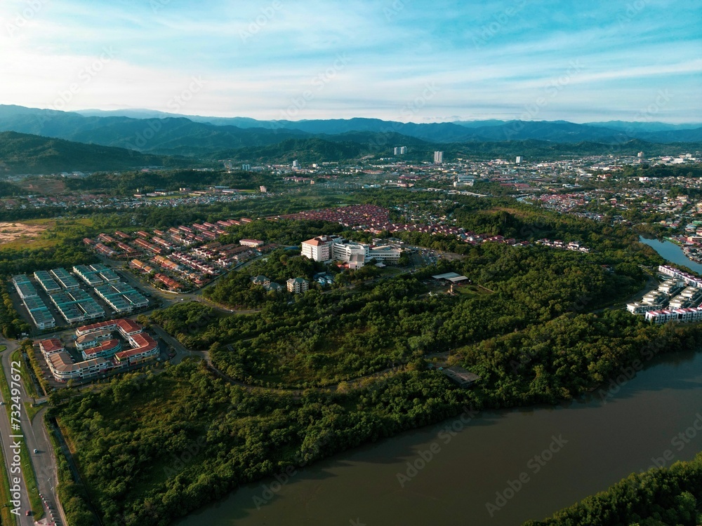 Aerial view of a bustling cityscape with a river and greenery on a sunny day