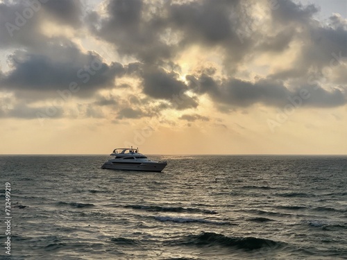 Scenic view of a white boat sailing in the sea during a picturesque cloudy sunset