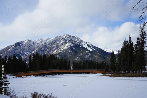 Arched bridge across a tranquil river at the foot of snow-capped mountains