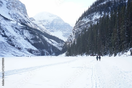 Couple enjoying a walk in a majestic winter landscape with a snow covered valley and mountain peaks