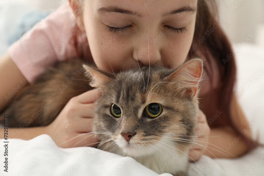 Cute little girl with cat lying on bed at home, closeup. First pet Cute little girl with cat lying on bed at home, closeup. First pet