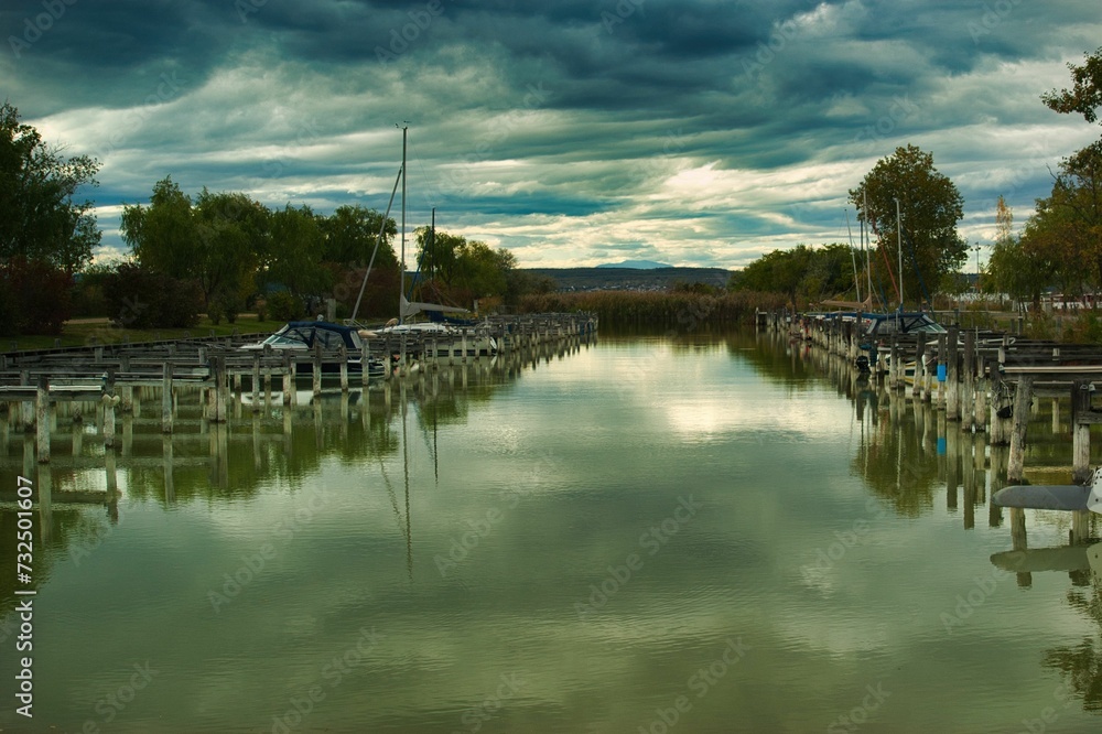 Fleet of boats peacefully moored in a marina in Illmitz, Austria, against dark and cloudy skies
