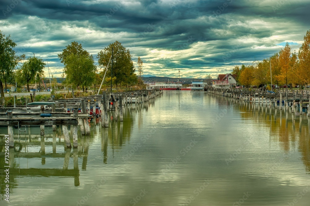 Fleet of boats peacefully moored in a marina in Illmitz, Austria, against dark and cloudy skies