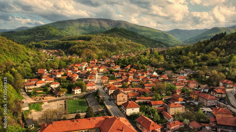 Aerial view of a town in green mountains on a sunny day