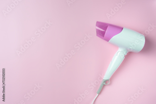 White hairdryer on a pink background. Copy space