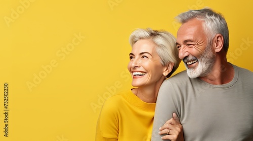 beautiful smiling bright couple 60 years old in comfortable clothes on a yellow background. The concept of a happy and prosperous life in retirement. Copy space