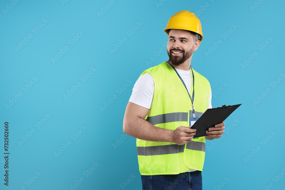Engineer in hard hat holding clipboard on light blue background, space for text Engineer in hard hat holding clipboard on light blue background, space for text