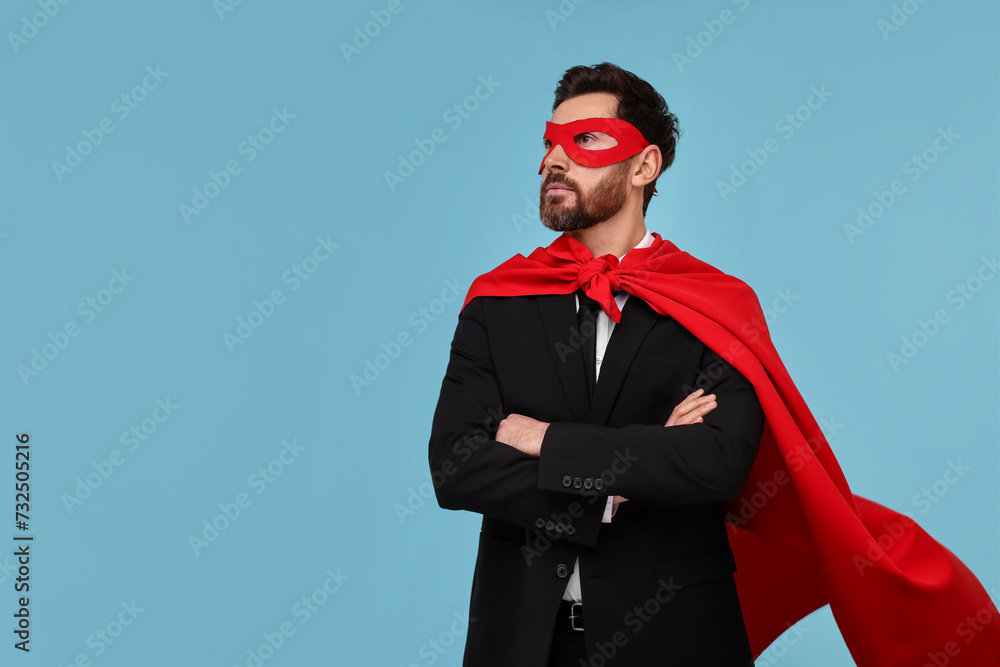 Businessman wearing red superhero cape and mask on light blue background. Space for text Businessman wearing red superhero cape and mask on light blue background. Space for text