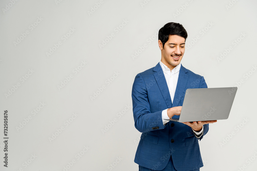 Businessman in blue suit is using laptop, a depiction of modern professionalism and digital engagement, concept of mobile business, suggesting ease of technology use and successful work outcomes