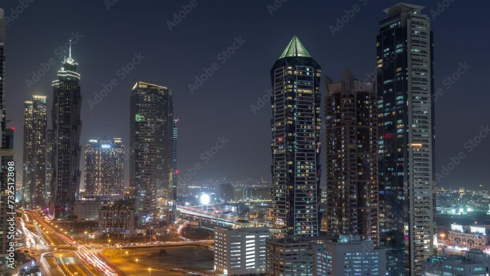 Business bay district skyline with modern architecture timelapse day to night transition after sunset from above. Aerial view of Dubai skyscrapers and towers near main highway. Traffic on a crossroad Business bay district skyline with modern architecture timelapse day to night transition after sunset from above. Aerial view of Dubai skyscrapers and towers near main highway. Traffic on a crossroad
