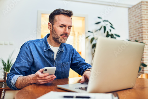Adult man at home doing online payment with two factor authentication on mobile phone photo