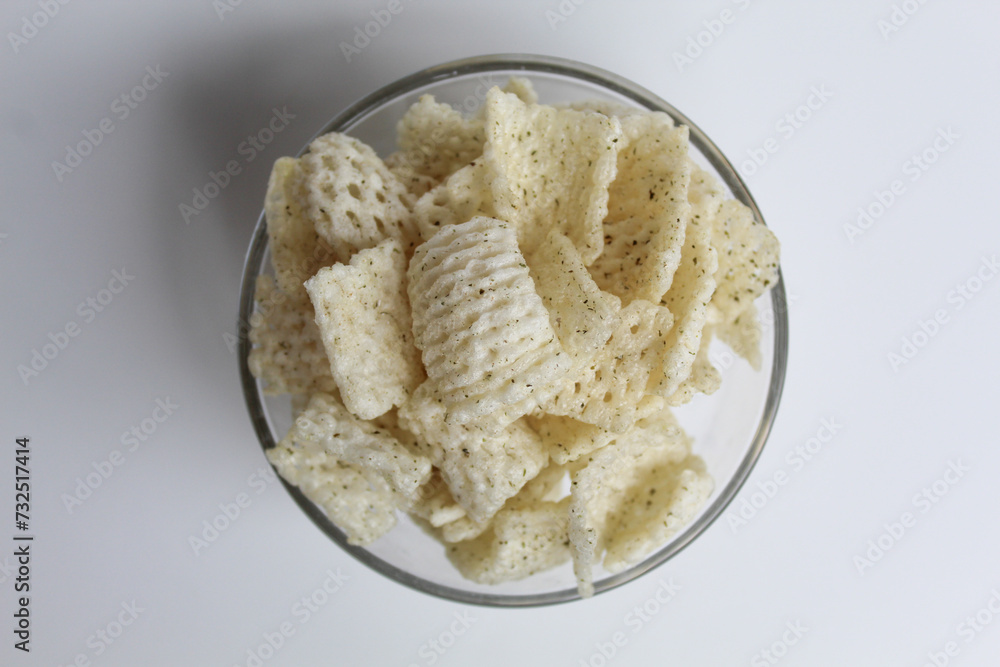 Crackers in net shape, in transparent glass bowl. isolated on white background, flat lay or top view Crackers in net shape, in transparent glass bowl. isolated on white background, flat lay or top view