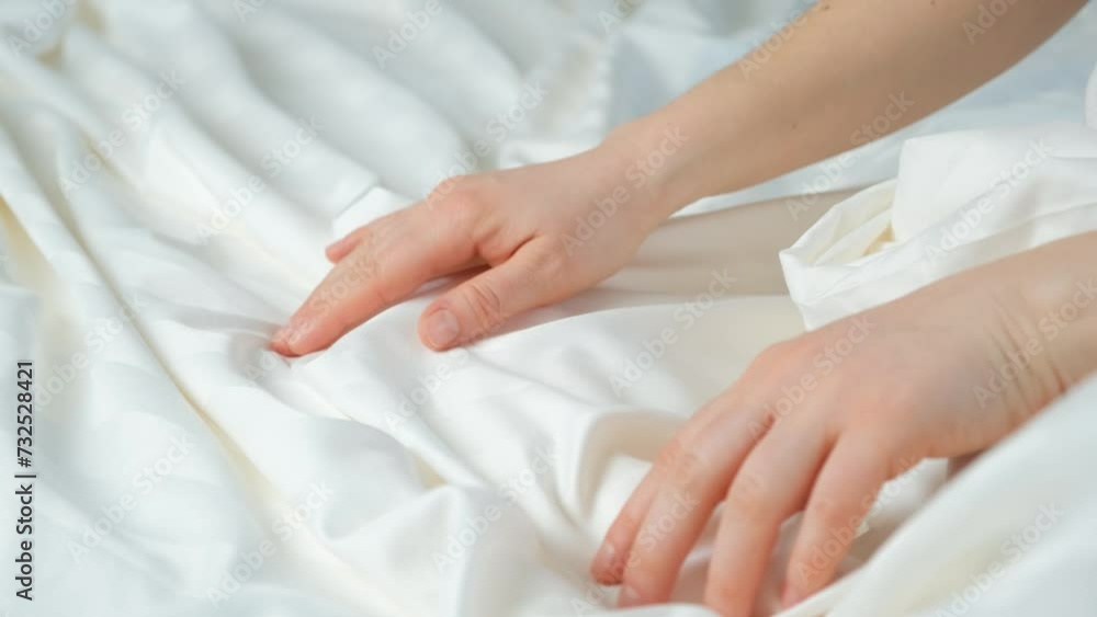 Woman touching the fabric of stripe satin with her hand, gently stroking, close-up