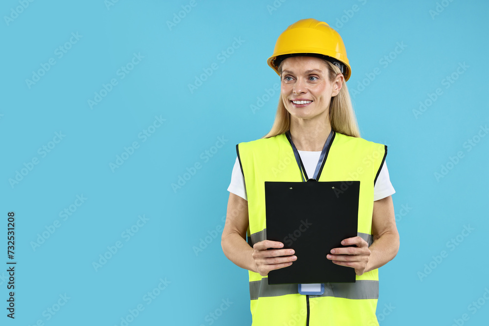 Engineer in hard hat holding clipboard on light blue background, space for text Engineer in hard hat holding clipboard on light blue background, space for text
