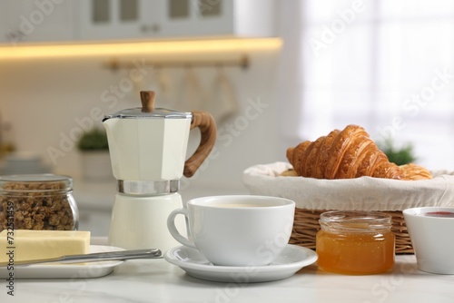 Fototapeta Naklejka Na Ścianę i Meble -  Breakfast served in kitchen. Fresh coffee, granola, croissants, jam, butter and honey on white table