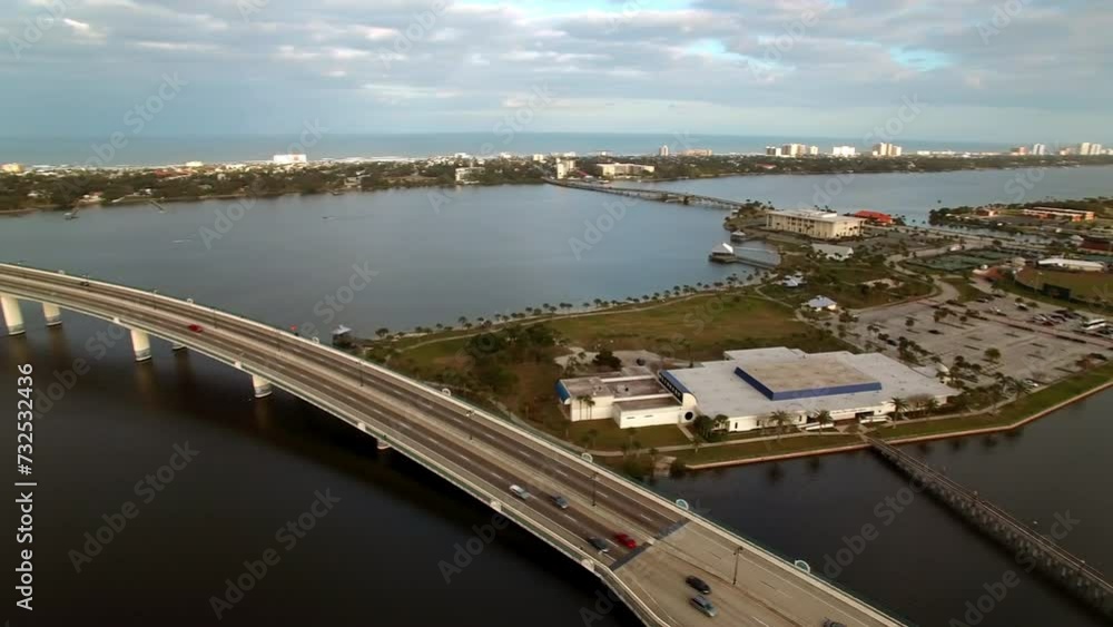 Aerial Panning Shot Of Cars Moving On Segmental Bridge Over River Under Cloudy Sky - Daytona Beach , Florida Aerial Panning Shot Of Cars Moving On Segmental Bridge Over River Under Cloudy Sky - Daytona Beach , Florida
