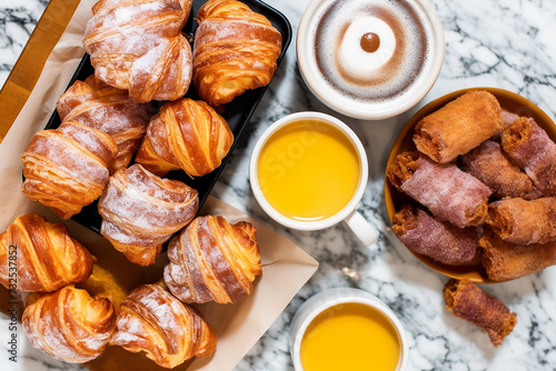 An assortment of pastries with coffee and juice on a marble surface.