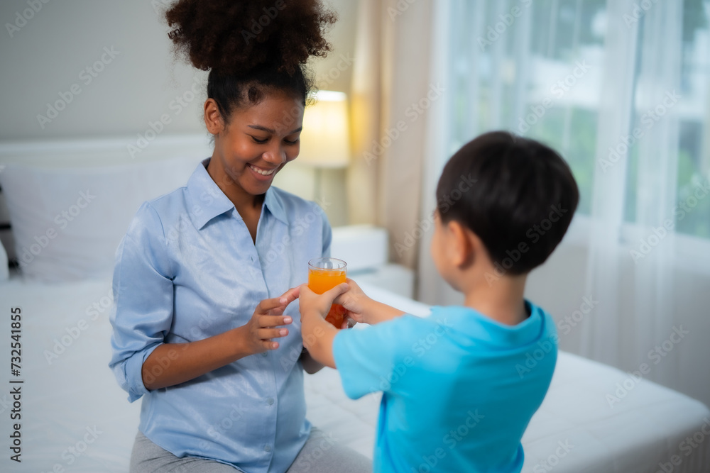 Young African American pregnant woman take a glass of orange juce from her son with smile of happiness at home, taking care, relationship, healthy concept. Young African American pregnant woman take a glass of orange juce from her son with smile of happiness at home, taking care, relationship, healthy concept.