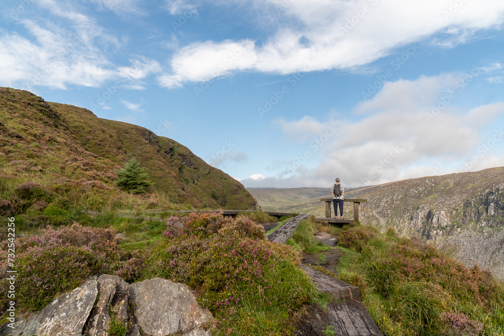 Hiker enjoying the view from the Spinc trail. Scenic Irish landscape from Glendalough in Wicklow Mountains.