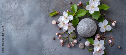 A gray background adorned with flowers, leaves, and a stone. A beautiful blend of flower arrangements and nature's art.