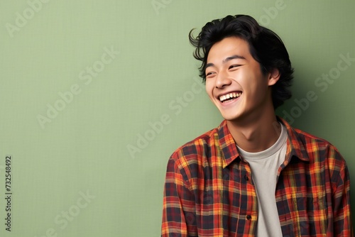 Portrait of a handsome young asian man laughing against green background