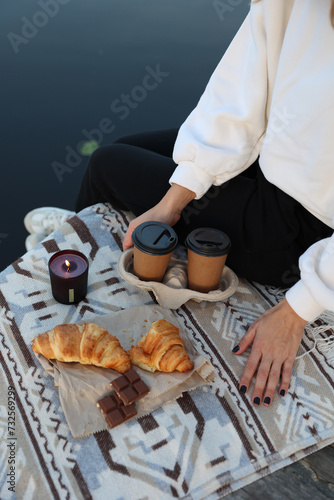 aesthetic photo. picnic on the pier with coffee and croissants, chocolate and candles