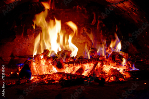 Bright flames rise energetically from burning wood logs.