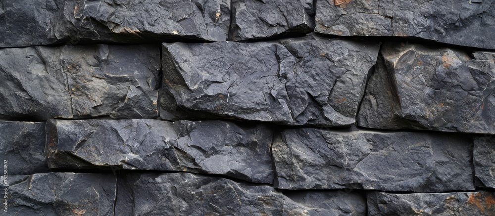 A grey stone wall, made of composite material, displays a pattern of rectangular rocks, resembling a bedrock formation. A grey stone wall, made of composite material, displays a pattern of rectangular rocks, resembling a bedrock formation.