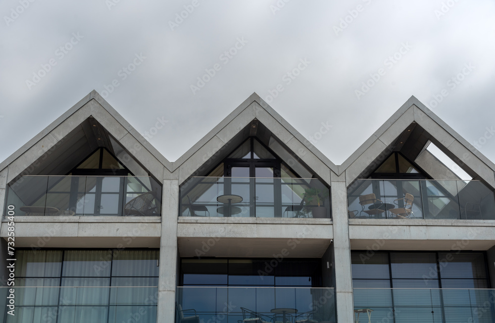 Modern hotel and house roof attics against cloudy sky. Home residential building. Traditional British houses Modern hotel and house roof attics against cloudy sky. Home residential building. Traditional British houses