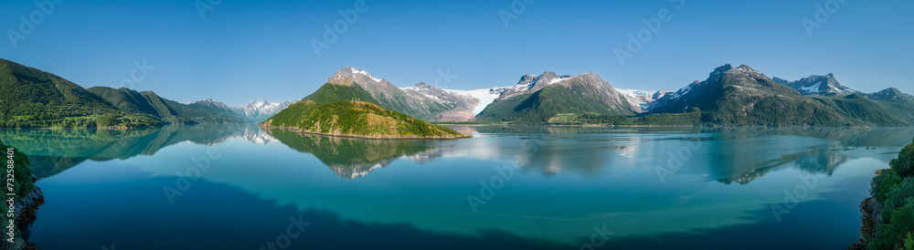 An idyllic super panorama of the Svartisen Glacier vicinity, with the Saltfjell mountain range reflected in the tranquil fjord waters of Norway