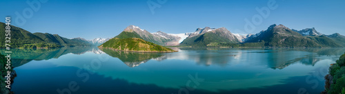 An idyllic super panorama of the Svartisen Glacier vicinity, with the Saltfjell mountain range reflected in the tranquil fjord waters of Norway © Artem